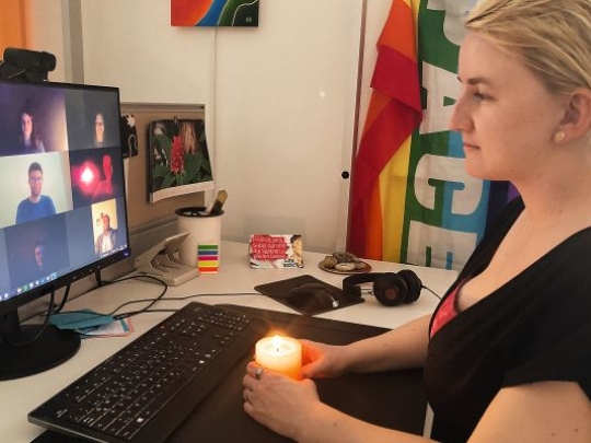 Frau mit brennender Kerze von einem Bildschirm mit Videokonferenz-Teilnehmenden 