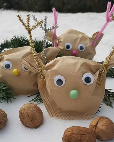 Rentiergesichter aus Filtertüten mit aufgeklebten Wackelaugen, daneben Tannenzweige und Walnüsse