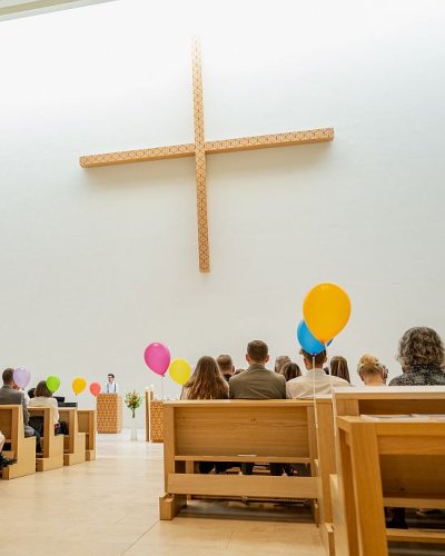 Menschen in Kirchenbänken mit Luftballons
