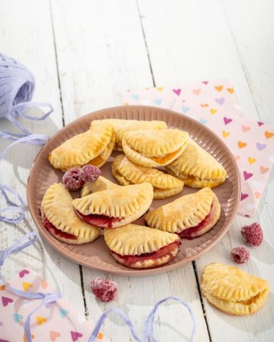 Quarktaschen mit roter Füllung und einzelne Himbeeren auf Schale