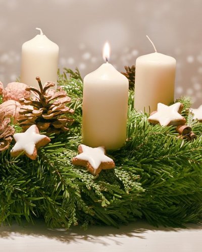 Adventskranz mit zwei brennenden weißen Kerzen