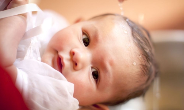 Baby über dessen Kopf Wasser rinnt 