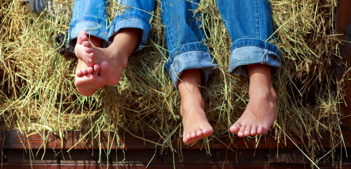 Kinderfüße in Jeans auf Heuboden