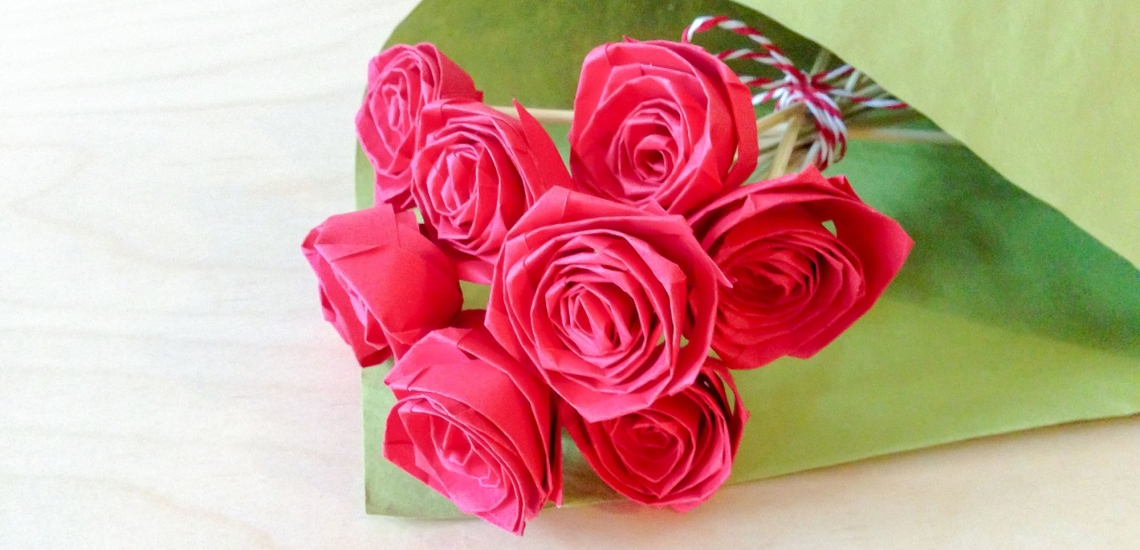 Strauß aus pinkfarbenen Papierrosen in grünem Papier