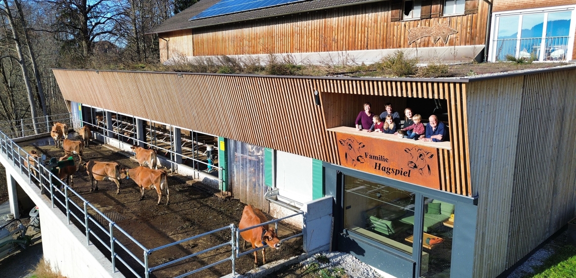 Bauernfamilie auf Balkon eines modernen neuen Kuhstalls mit Rindern