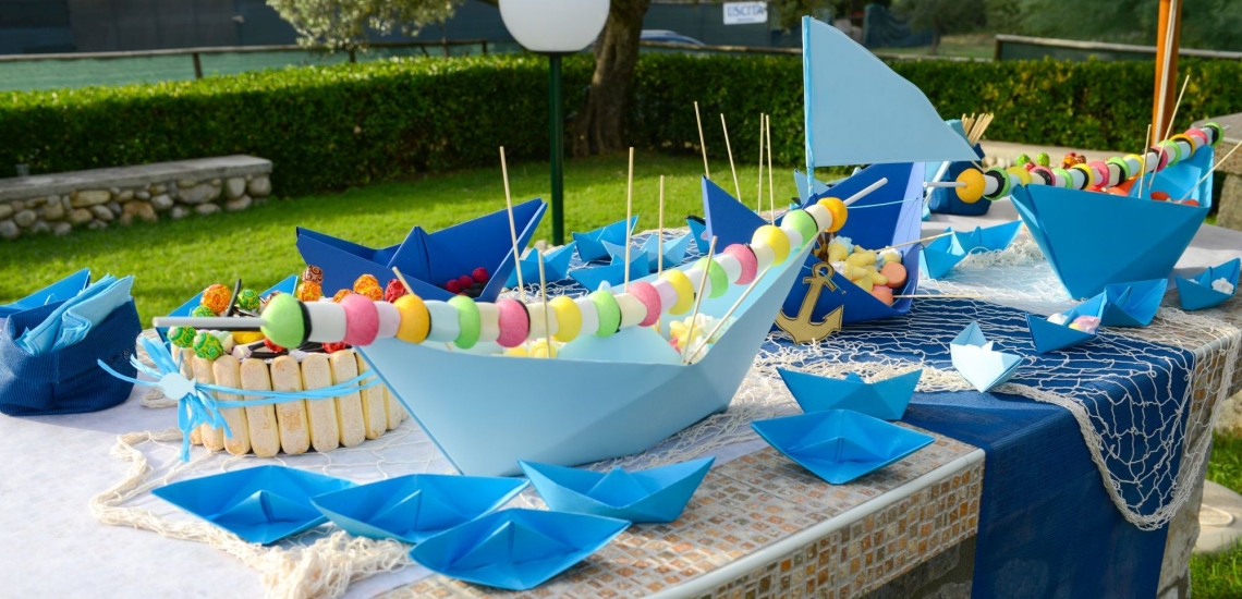 Gartentisch mit bunter Deko mit Papierschiffen und Süßigkeiten