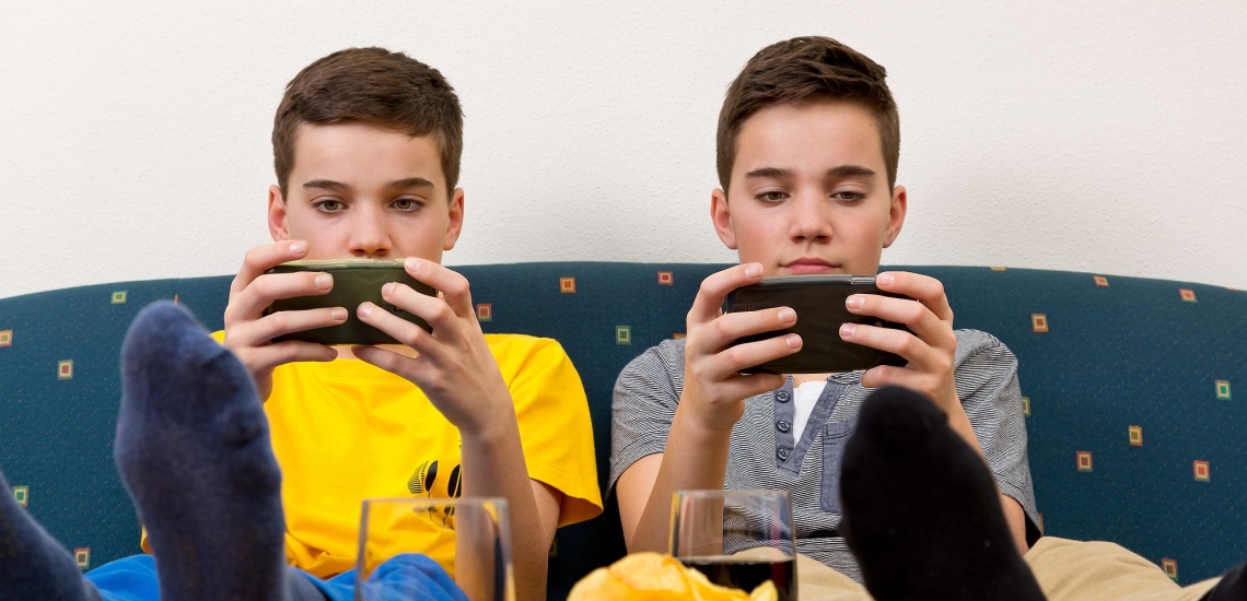 zwei Jungen sitzen auf Sofa und schauen in ihre Handys
