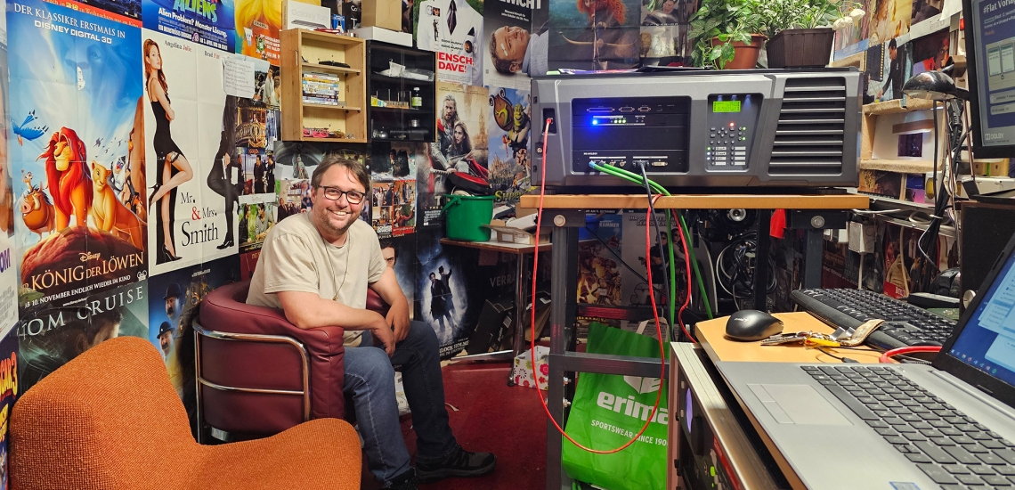 Roman Sorger im Schnittraum umgeben von vielen Filmplakaten