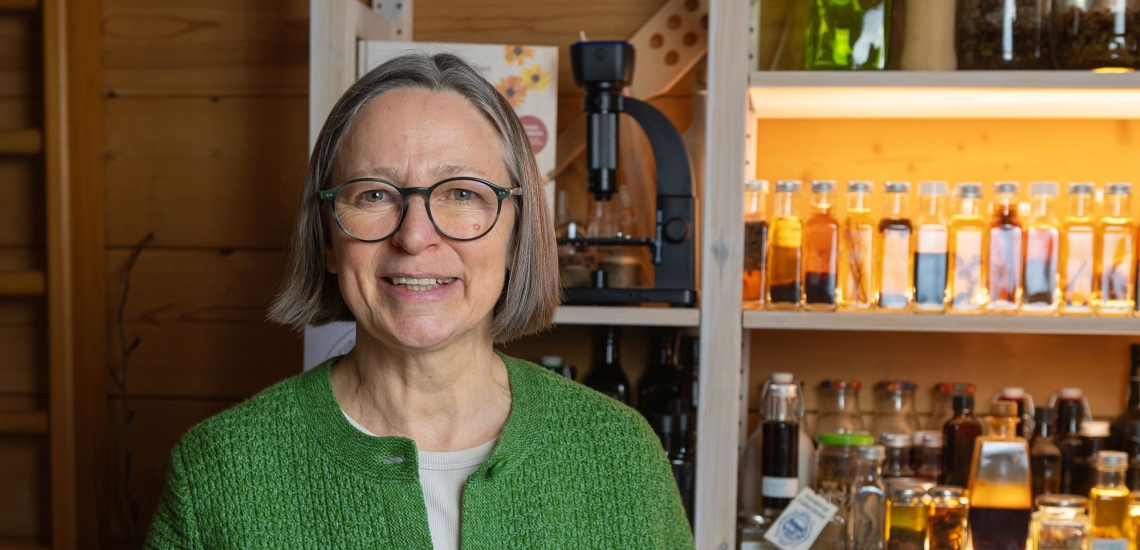 Porträt Karin Buchart vor Regal mit Miskroskop, Buch und vielen Fläschchen