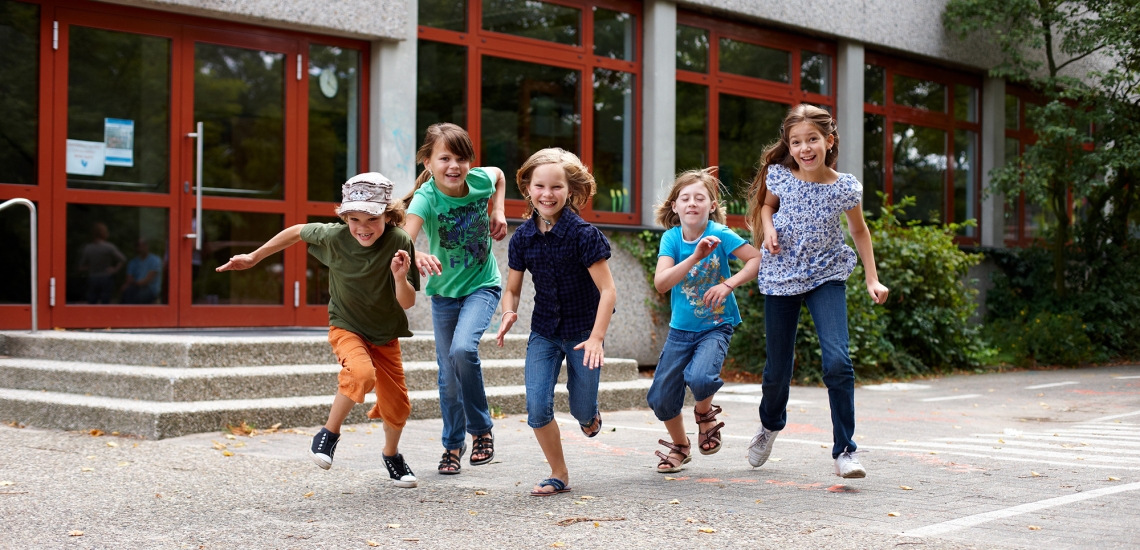 Kinder rennen über den Pausenhof einer Schule.