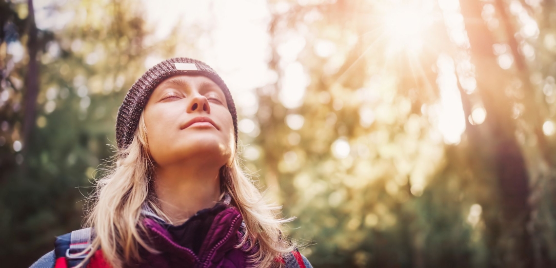 junger Mensch mit Mütze in Natur träumt mit geschlossenen Augen