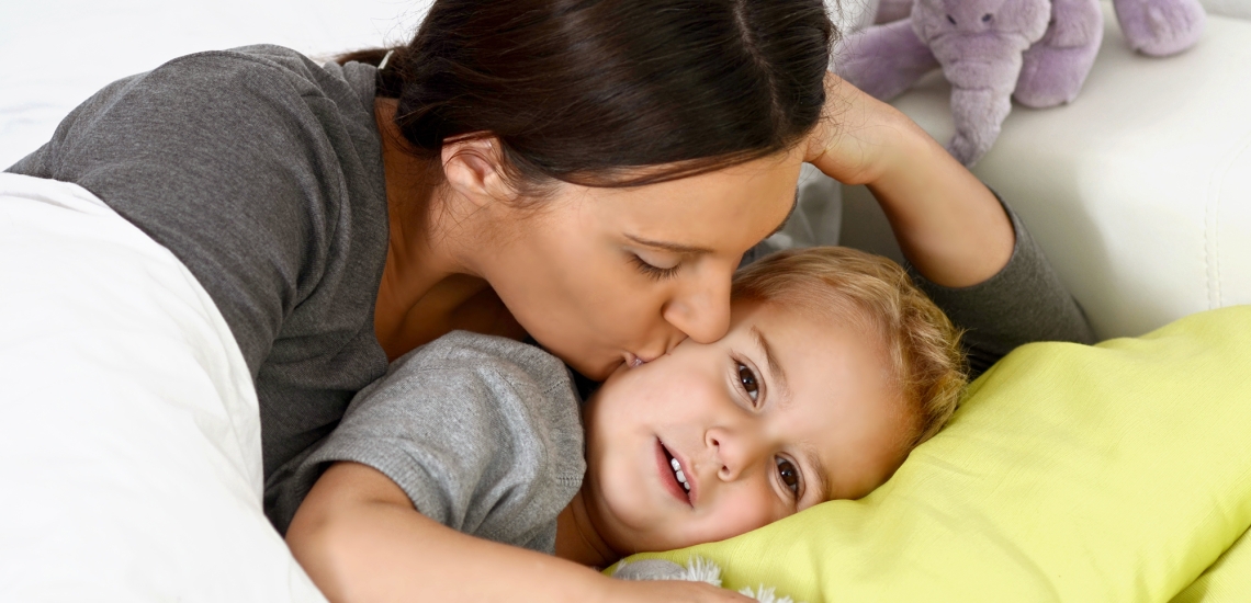 Eine Mutter kuschelt mit ihrem Sohn im Bett.