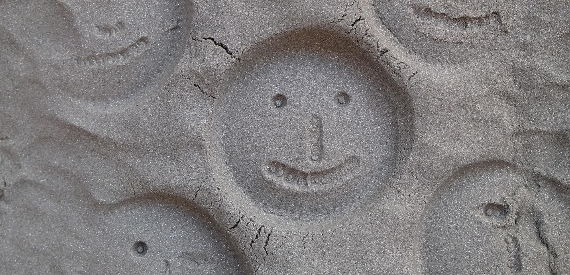 In Sand gedrückte und geformte Gesichter