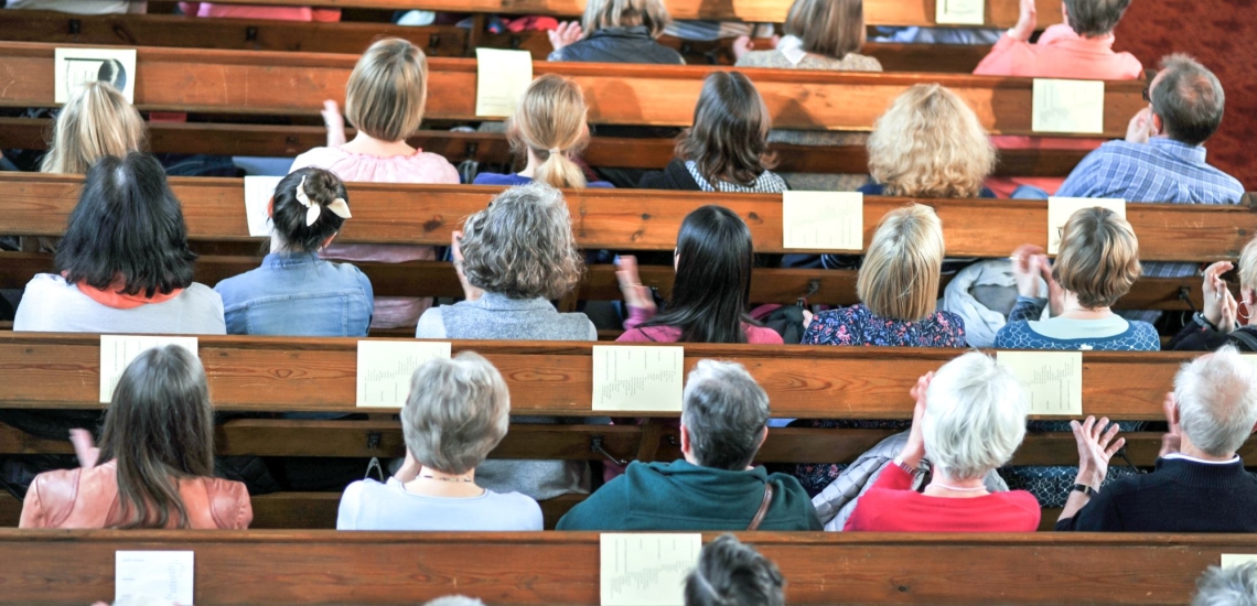 Gottesdienstgemeinde in Kirchenbänken von oben