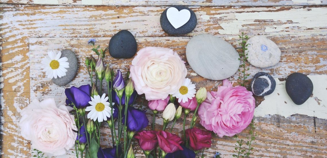 Blumen und Steine auf einem rauen Holzbrett