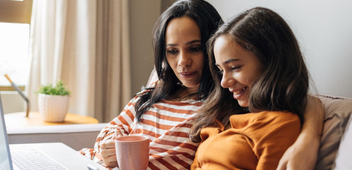 Mutter und Tochter sitzen auf dem Sofa und sprechen vertraut miteinander