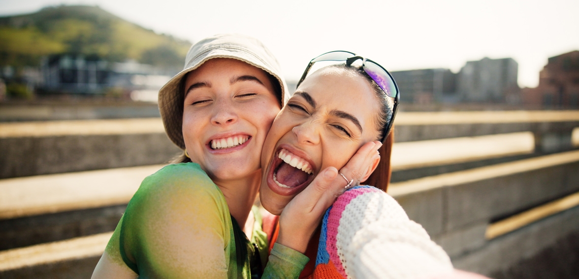 Zwei junge Frauen posieren fröhlich für ein Selfie.