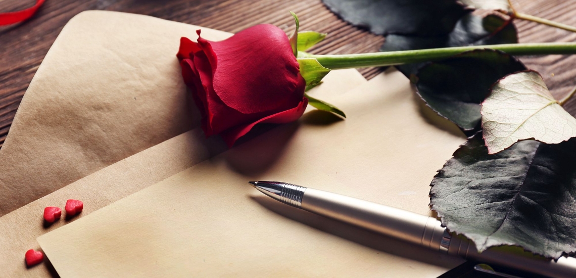 Briefpapier mit Stift, roter Rose und Herzen