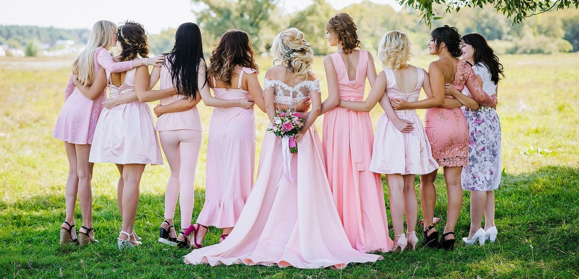 Weibliche Hochzeitsgäste mit Braut in eleganten Kleidern auf einer Wiese