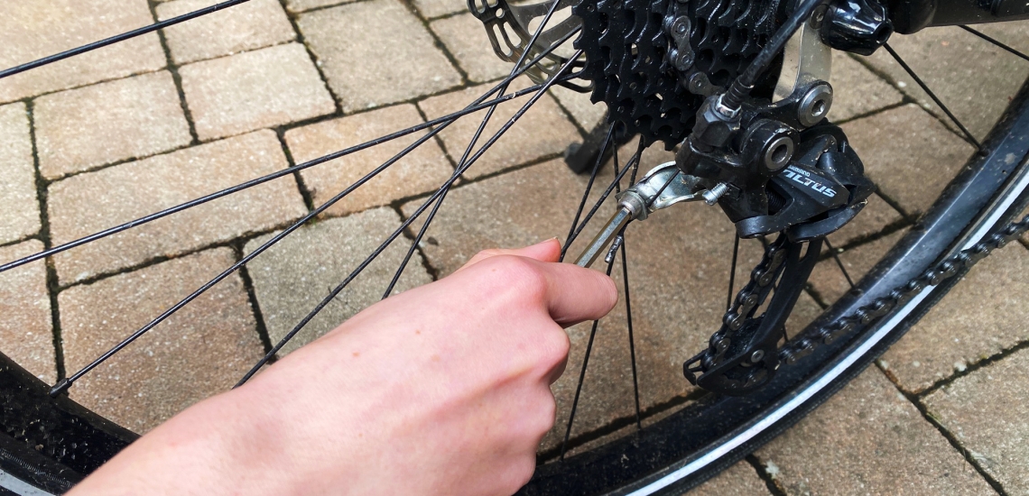 Hand mit einem Werkzeug schraubt an einem Fahrrad.