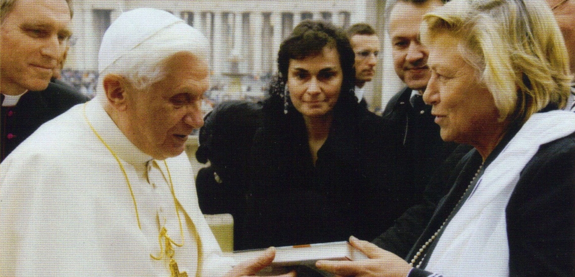 Papst nimmt Buch von Frau entgegen, im Hintergrund weitere Personen