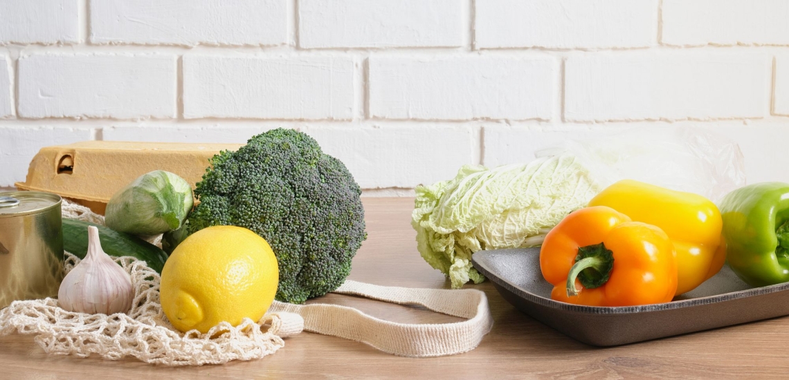 Obst, Gemüse, Salat und Eier mit Einkaufsnetz liegen auf einer Arbeitsfläche in der Küche