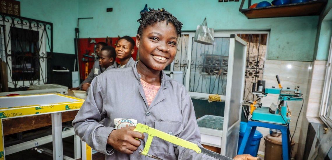 Jugendliche in einer Werkstatt, eine von ihnen hält eine Säge