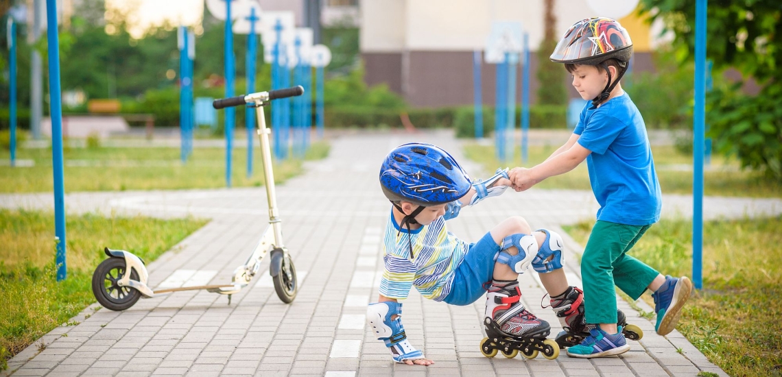 Kind hilft anderem Kind, das mit Inline-Skates hingefallen war, wieder auf