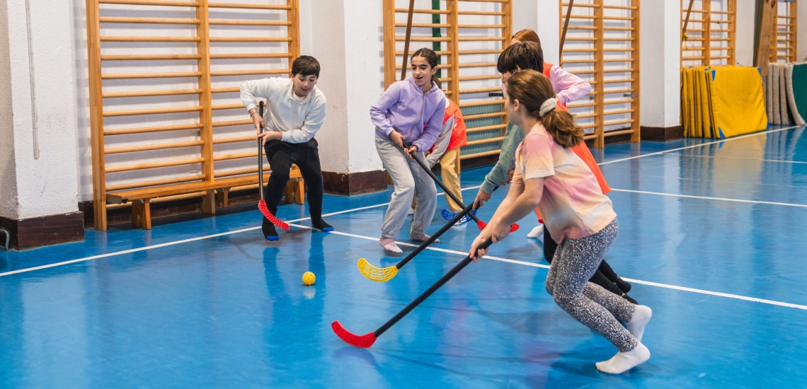Jugendliche spielen Hockey in Turnhalle