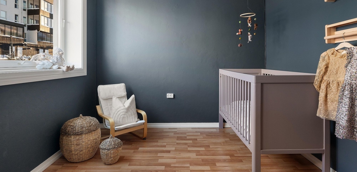 Babyzimmer mit Babybett, Sessel, Aufbewahrungskörben, Mobile und Garderobe