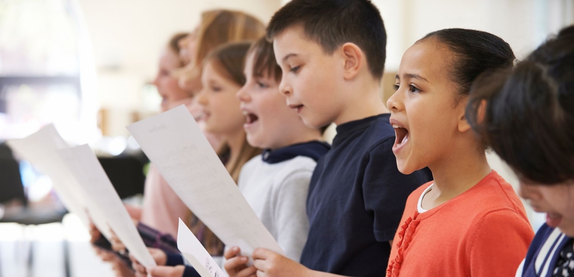 Schülerinnen und Schülern stehen im Schulchor in einer Reihe und singen nach Noten