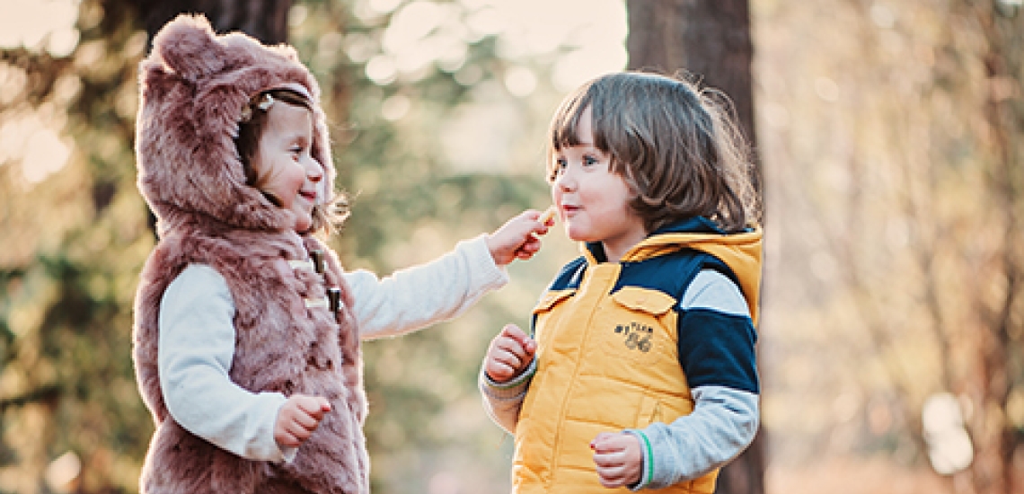 Zwei Kinder im herbstlichen Wald teilen Süßigkeiten