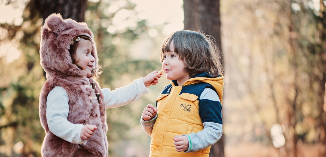 Kinder in herbstlichem Wald teilen Süßigkeiten