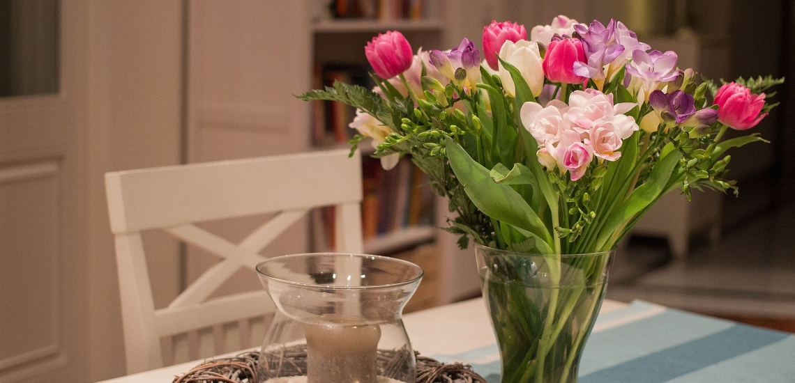 Wohnzimmer mit weißen Möbeln, Windlicht und Blumenstrauß