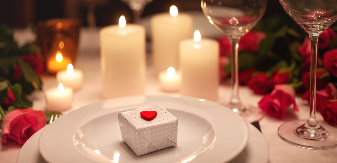 Festlich gedeckter mit Rosen, Kerzen und einem kleinen Geschenk