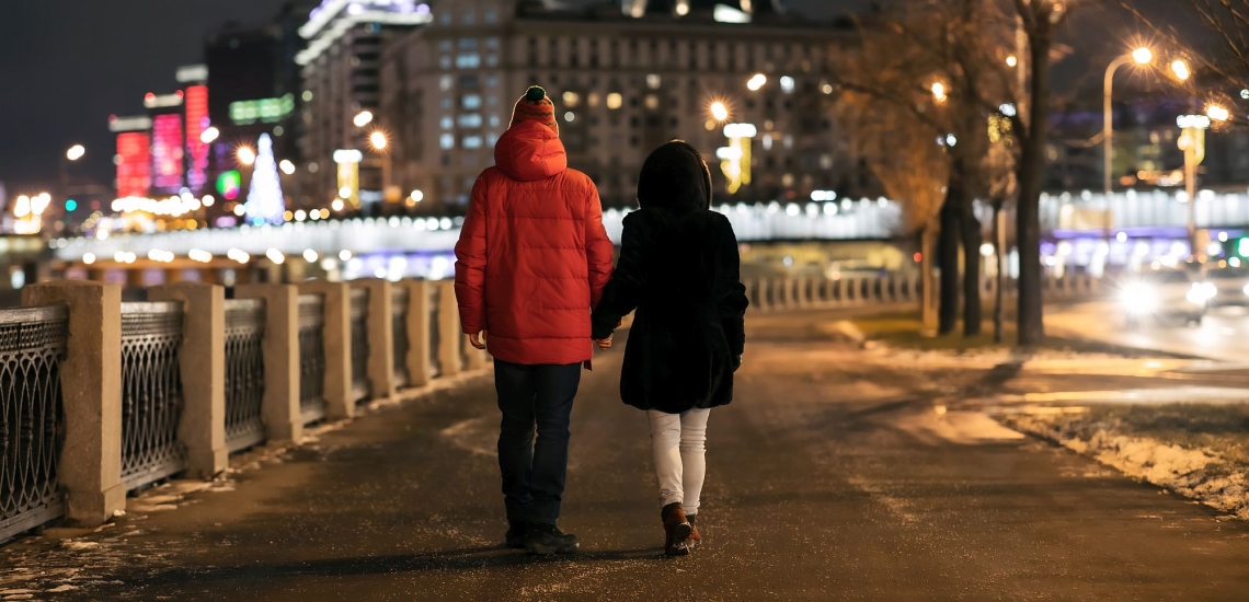 Ehepaar spaziert am Abend Hand in Hand durch eine Stadt