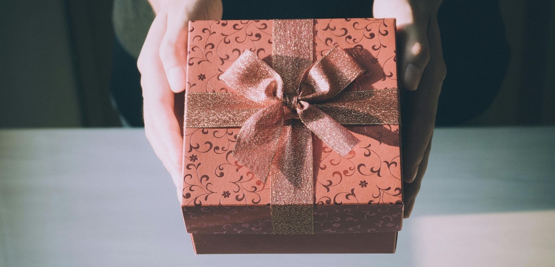 Hände halten elegante Geschenkschachtel mit großer glitzernder Schleife