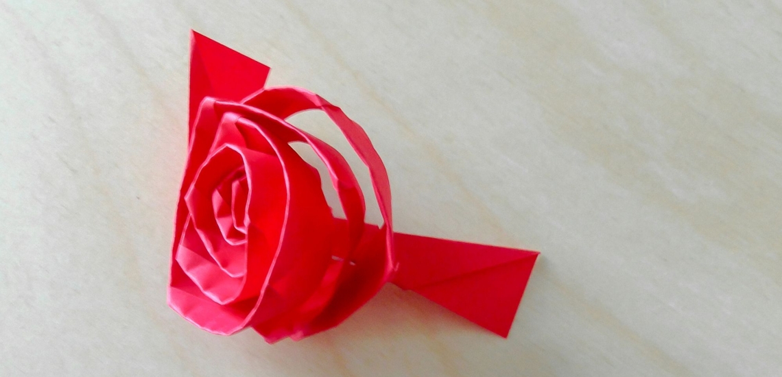 zu einer Rosenblüte gerollter Papierstreifen