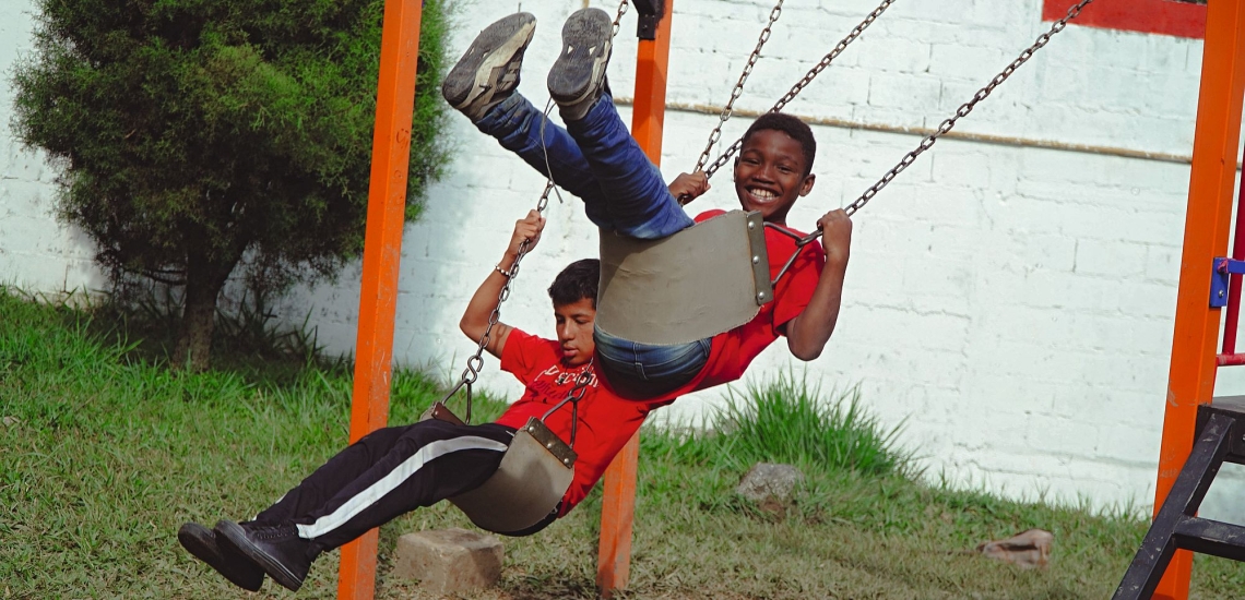 Zwei Kinder schaukeln im Ausbildungszentrum der Ciudad Don Bosco in Medellín