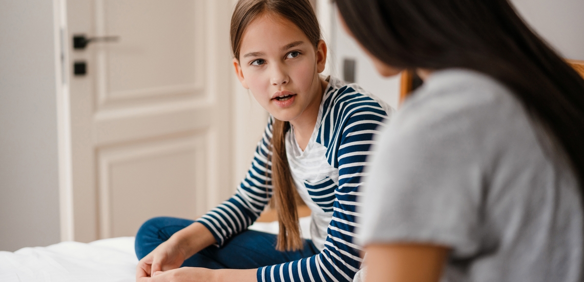 Mädchen unterhält sich mit Mutter auf Bett