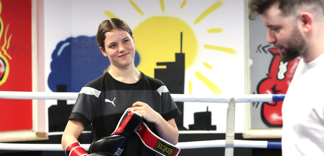 Marina Siewert steht im Boxring und zieht sich ihre Boxhandschuhe an.