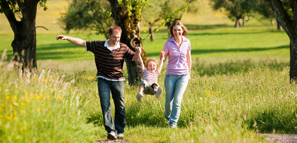 Vater, Mutter und Kind beim Spaziergang im Grünen