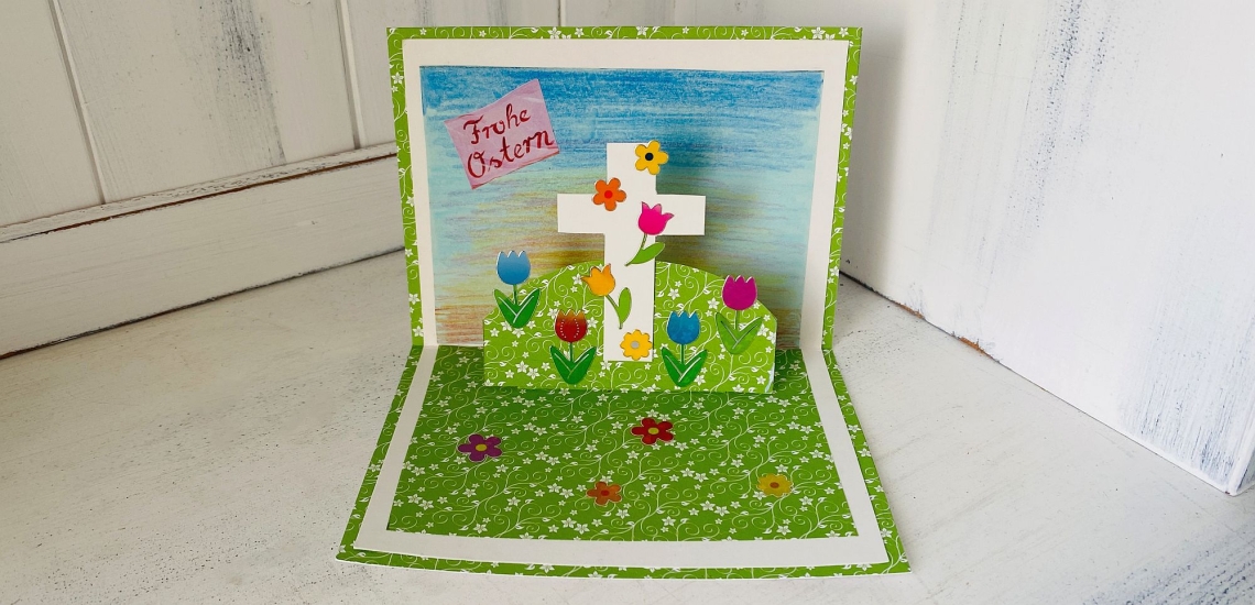 Popup-Karte mit Kreuz, Blumen, Himmel und Aufschrift Frohe Ostern