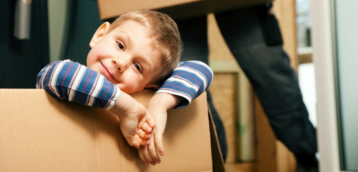 Kind schaut leicht skeptisch aus Umzugskarton