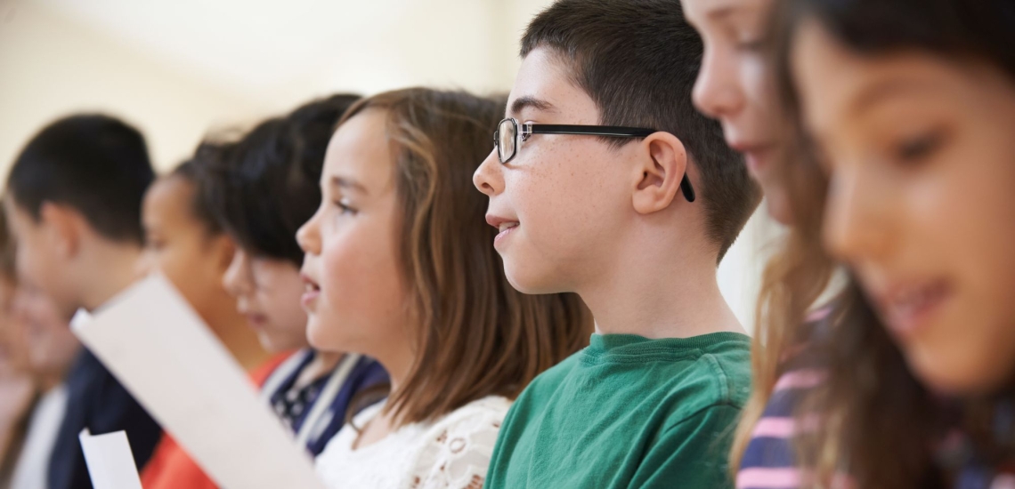 Kinder stehen in Reihe mit Blätter und hören oder singen