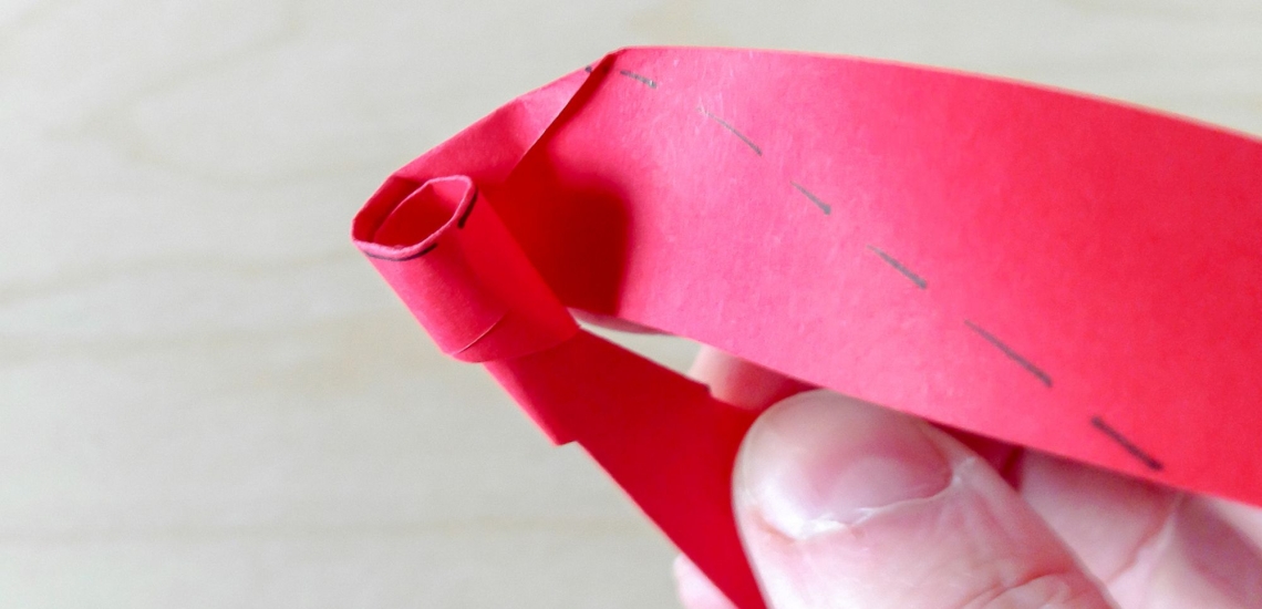 Hand mit gefaltetem und eingerolltem Papierstreifen