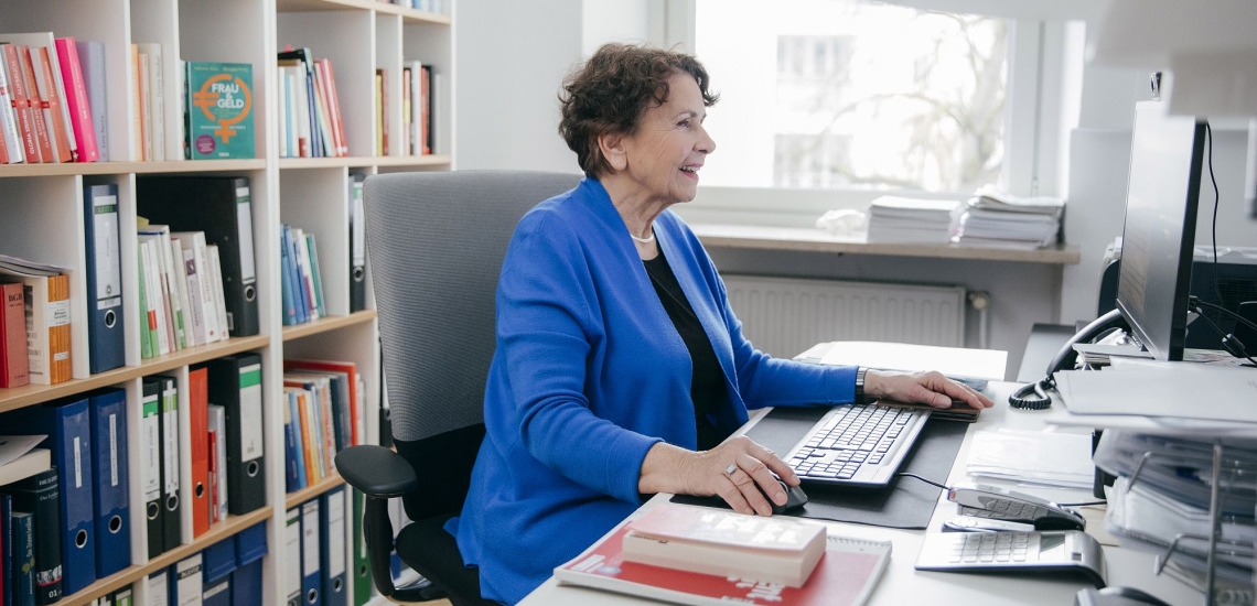 Helma Sick in Büro am Schreibtisch vor Bildschirm