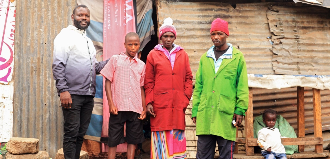 Jugendlicher mit Erwachsenen und Kleinkind vor Blechhütte in Nairobi