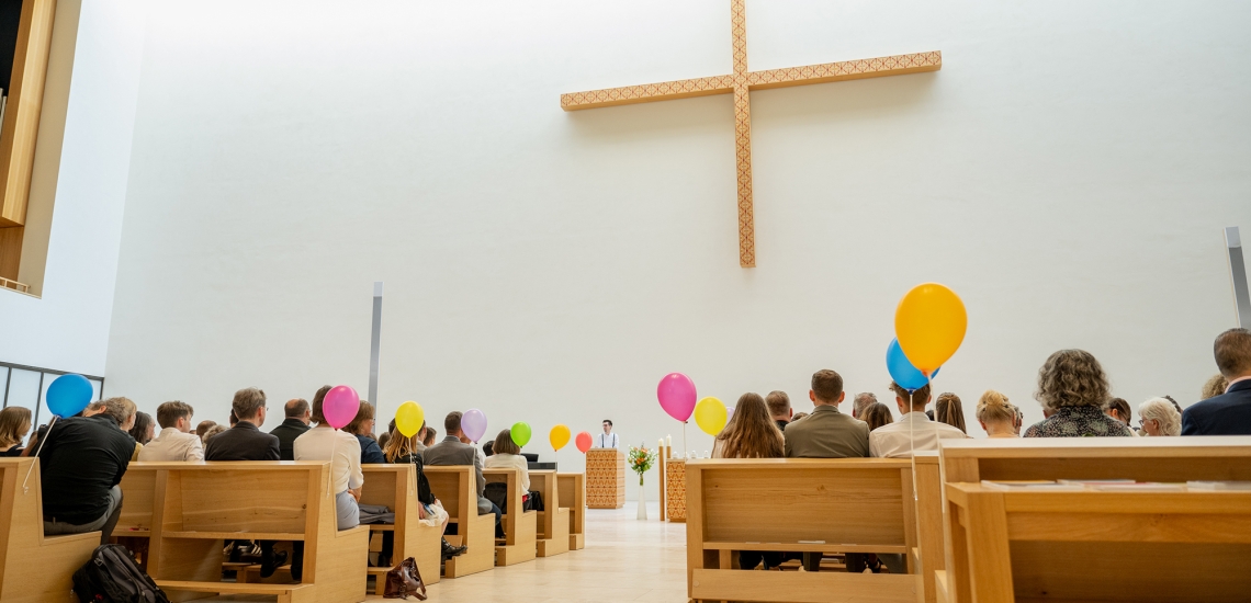 Menschen in Kirchenbänken mit Luftballons