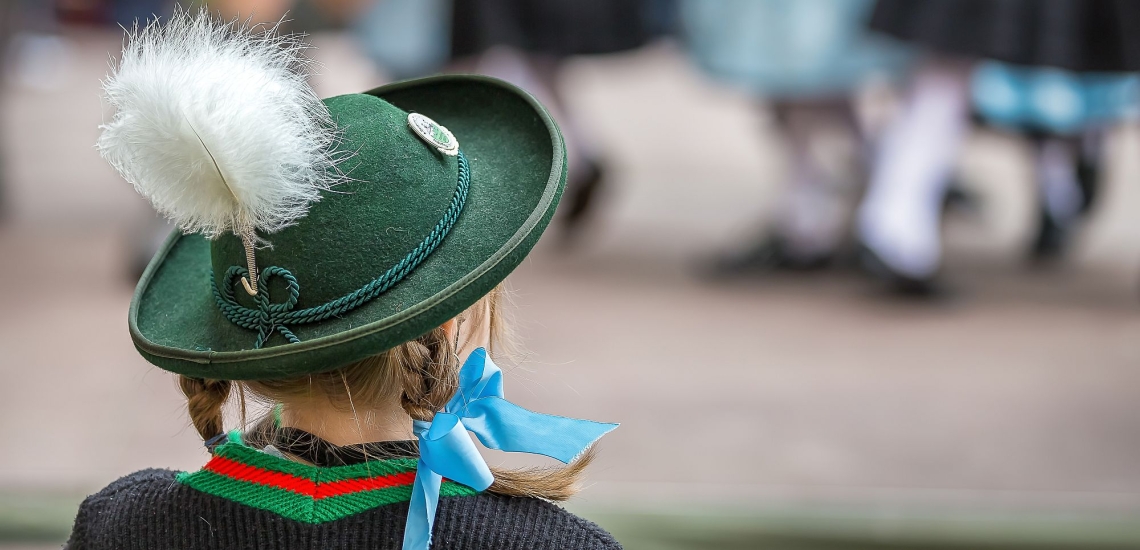 Mädchen in Tracht schaut einer Tanzgruppe zu